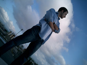 a man in a light blue shirt with a folded arms power pose gazing out of shot