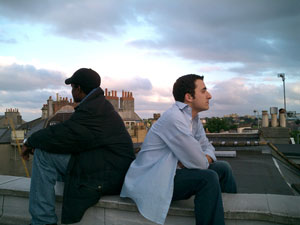 two men sitting back to back of the roof of a house